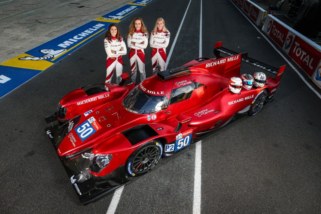 Equipe de mulheres Richard Mille: As corredoras de automobilismo, Tatiana Calderón, Katherine Legge e Sophia Floersch posando ao lado do carro de corrida vermelho.