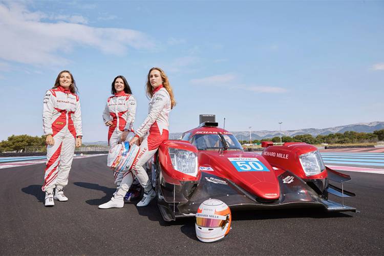 Equipe de mulheres Richard Mille: As corredoras de automobilismo, Tatiana Calderón, Katherine Legge e Sophia Floersch posando ao lado do carro de corrida vermelho.
